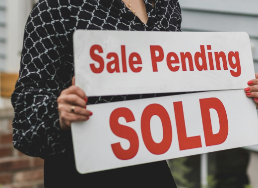 Female Real Estate Agent Holding Sale Pending and Sold Signs